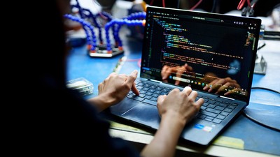 A person editing code on a laptop in a lab.