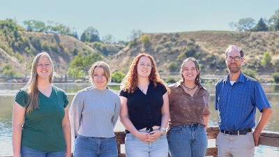 Researchers posing for a group photo by a reservoir.