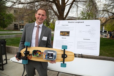 Cardon Blankenship posing for a photo with a longboard he electrified.