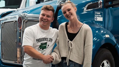 People shaking hands in front of a semi truck.