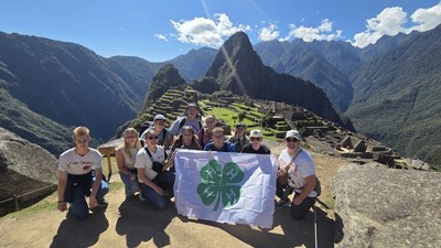People posing with a 4-H flag in front of Machu Picchu.