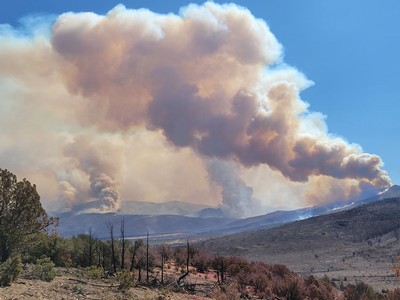 Smoke rising from a wildfire on a mountainside.