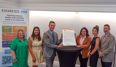 People posing with a document at an event.