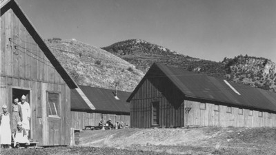 Cooks standing near mountain cabins.