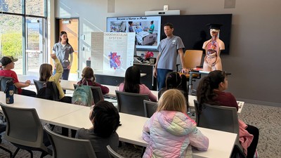 People teaching grade-school students about nursing in a classroom.