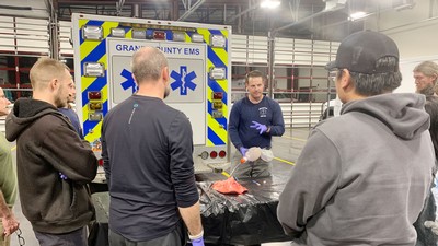An instructor demonstrates EMT skills in an ambulance garage.