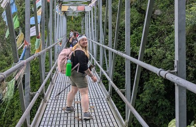 People crossing a foot bridge while hiking in Nepal.