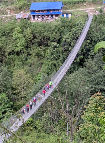 People crossing a foot bridge while hiking in Nepal.