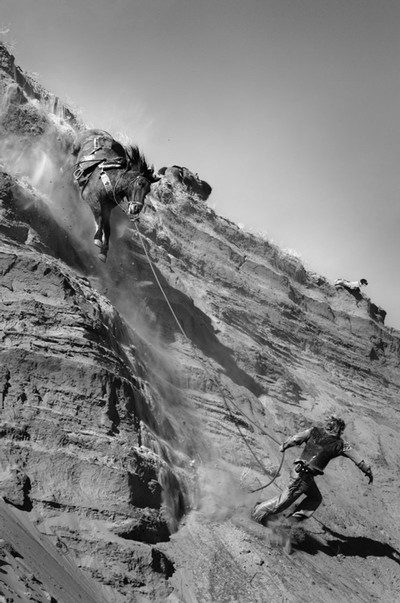 A man and a horse running down a steep embankment.