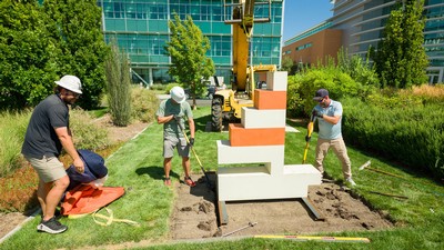 Workers installing a sculpture of a pixelated sailboat.