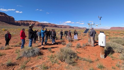 People looking at a weather station in the desert.