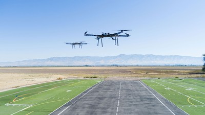 Drones flying above pavement in a rural area.