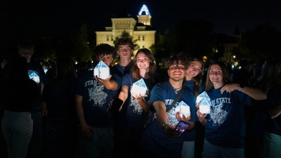 Students holding A-shaped lanterns in front of Old Main.