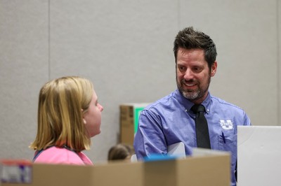 A professor speaking with a middle school student at a science fair.
