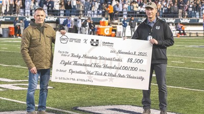 Two people holding a giant check at a football game.