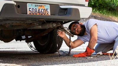 Motasem Abualqumboz checks the tailpipe of a truck.
