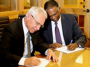 USU President Stan Albrecht and President Spalding Jugganaikloo signing a partnership agreement