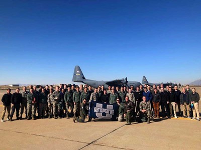 USU Air Force ROTC cadets pose with USU flag in front of a C-130 cargo plane.