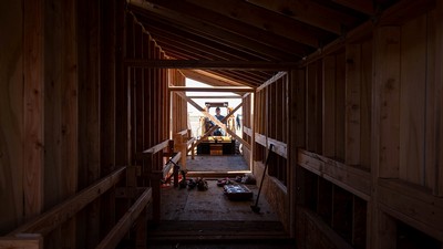A man operates a skid steer to connect the coop sections together