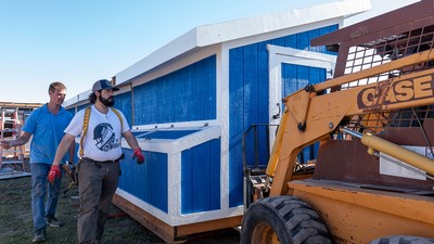Image shows two men speaking with a skid steer operator