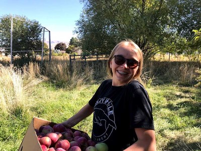 volunteer with a bushel of apples