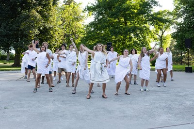 Students wearing togas perform a dance outdoors.