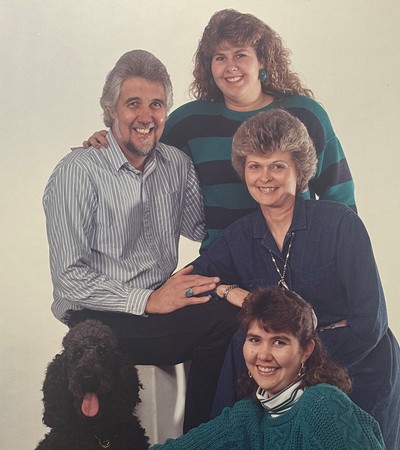 An old family photograph featuring four people and a dog.