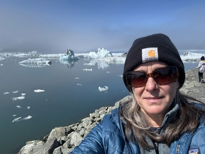Karen Beard on a rocky, icy beach.