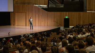 A man stands on a stage speaking to a crowd