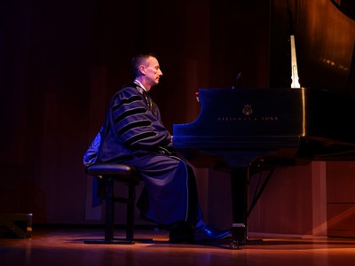 A man sits at a piano ready to play a song