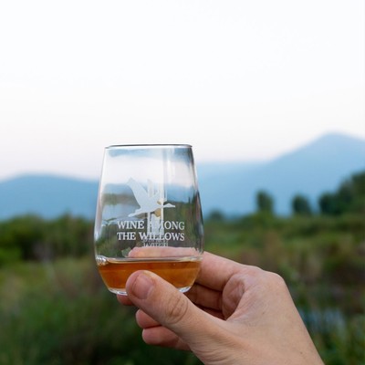 A hand holding up a wineglass with the Wine Among the Willows Logo.