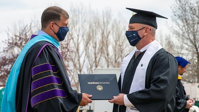 Associate Vice President James Y. Taylor presenting Nathan Rawlings with his diploma.