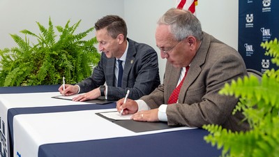 Brad Mortensen and Todd Combs signing documents.