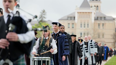People walk along USU's Quad in cap and gown