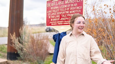 A woman stands in front of a marker near a lake.