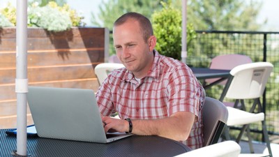 man sitting outside and using his computer.