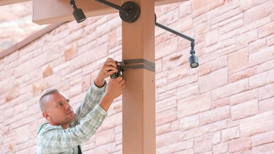 Zach Miller from the Institute of Outdoor Recreation adjusts a motion sensor camera.