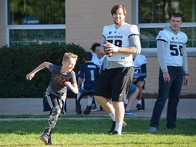 USU football players with Sound Beginnings students