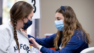 USU student receiving a vaccine from a USU Nursing student.