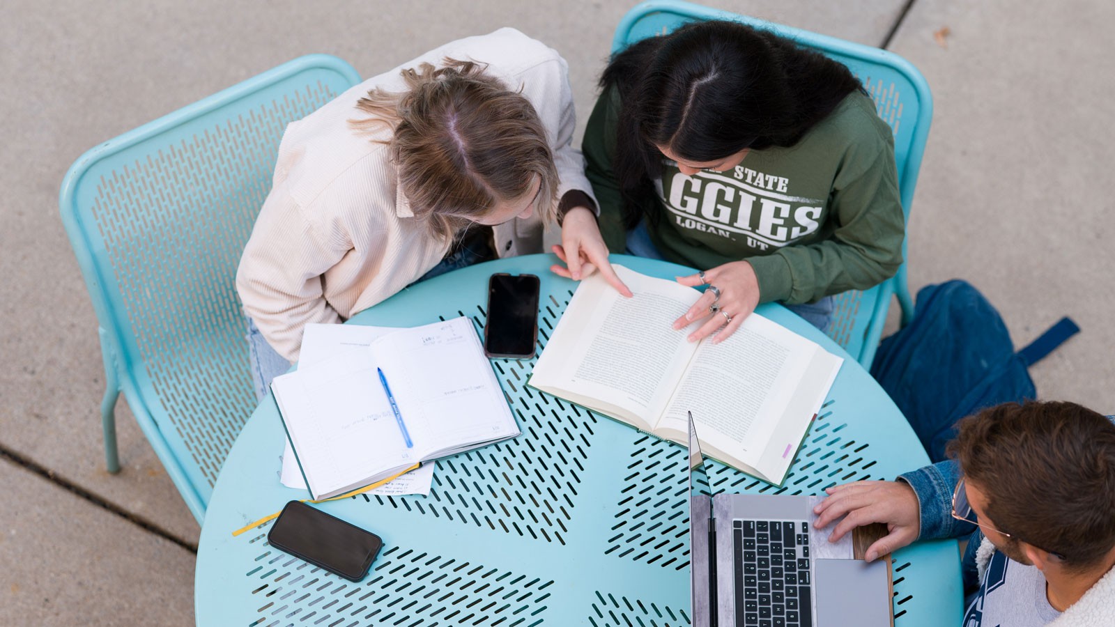 People studying at a table outdoors.