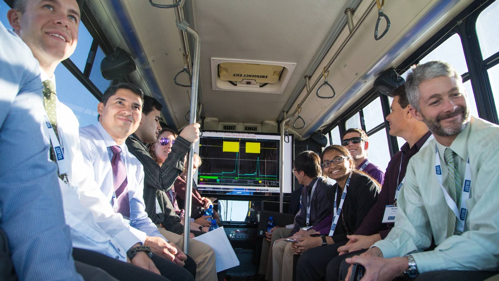 People in business attire ride an electric bus during a demonstration.