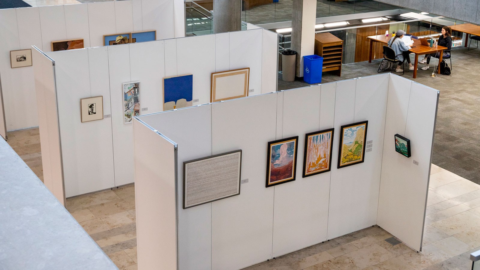 Paintings hang on an exhibit wall at the Merrill-Cazier Library at USU in Logan.
