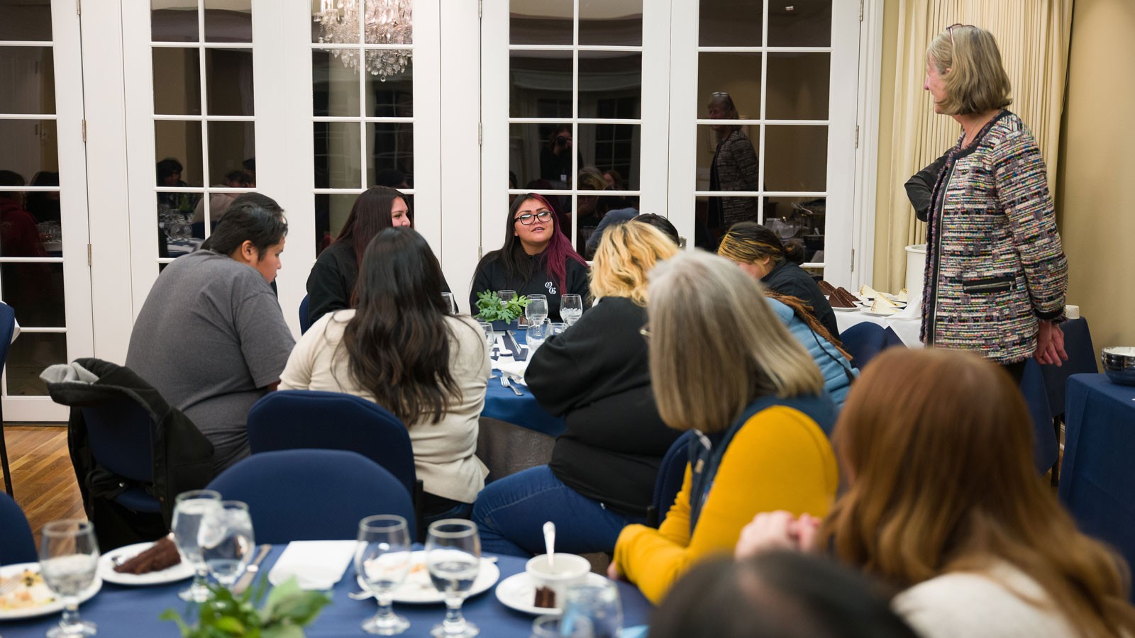 Noelle Cockett speaking with high schoolers at a dinner.