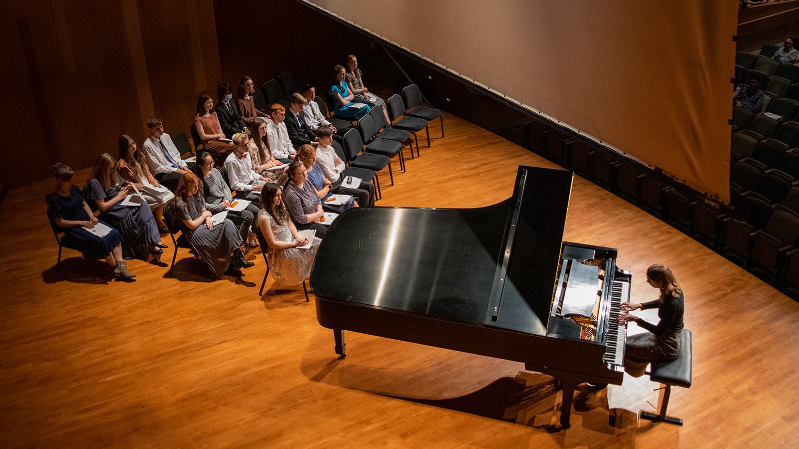 A person playing a piano while others listen.
