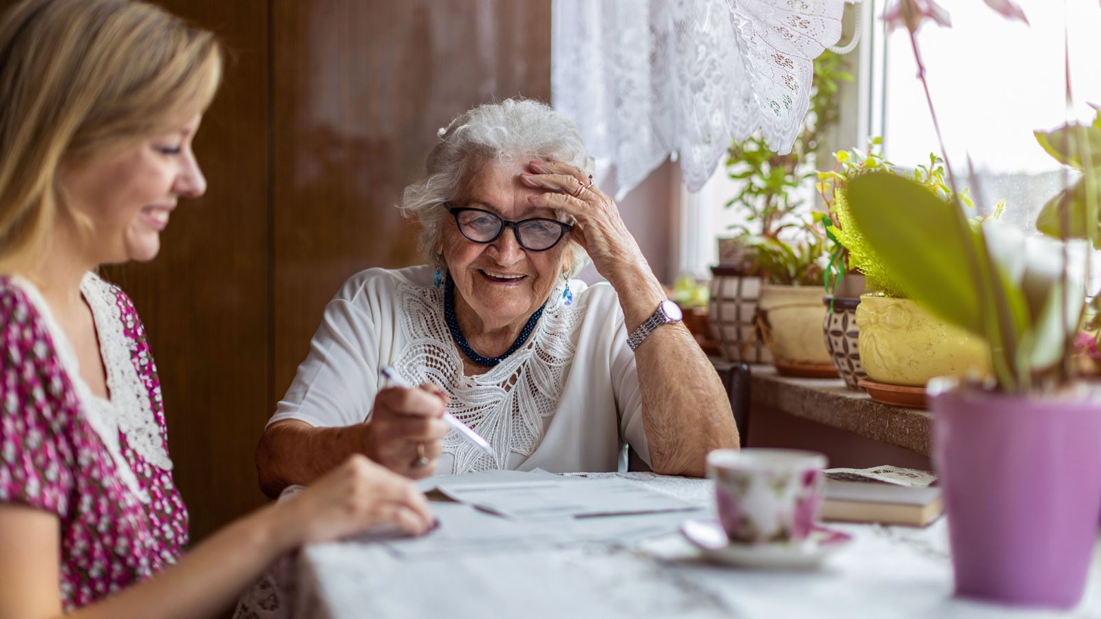 An older woman and younger woman sit at a table.