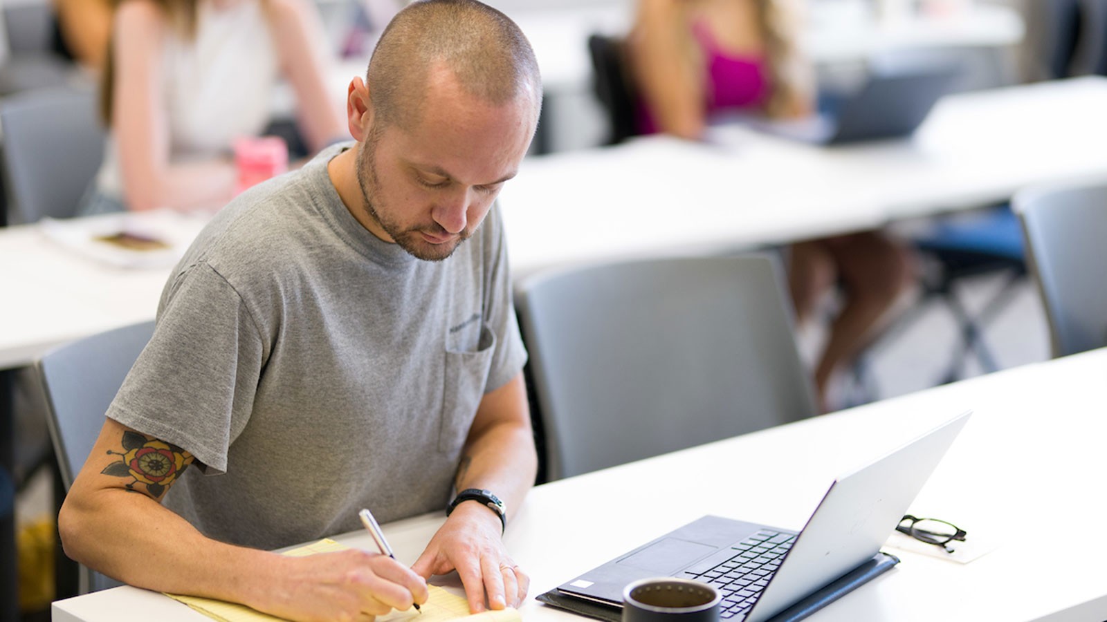 A person writing in a classroom.