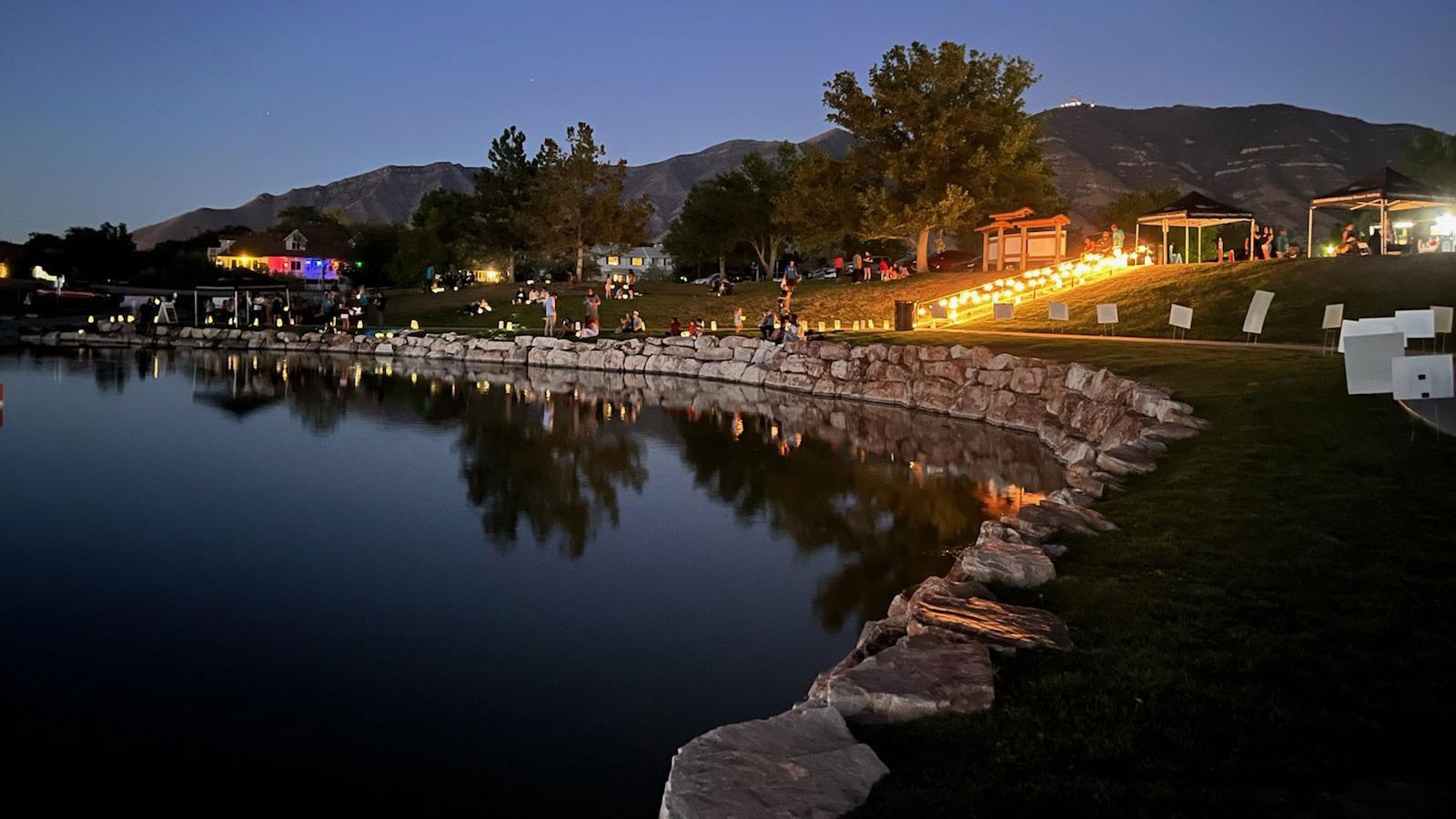 People with lanterns on a lake shore.