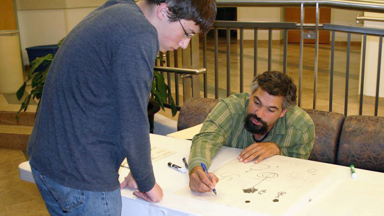 Jeff Hazboun drawing physics illustrations for a student at an event.