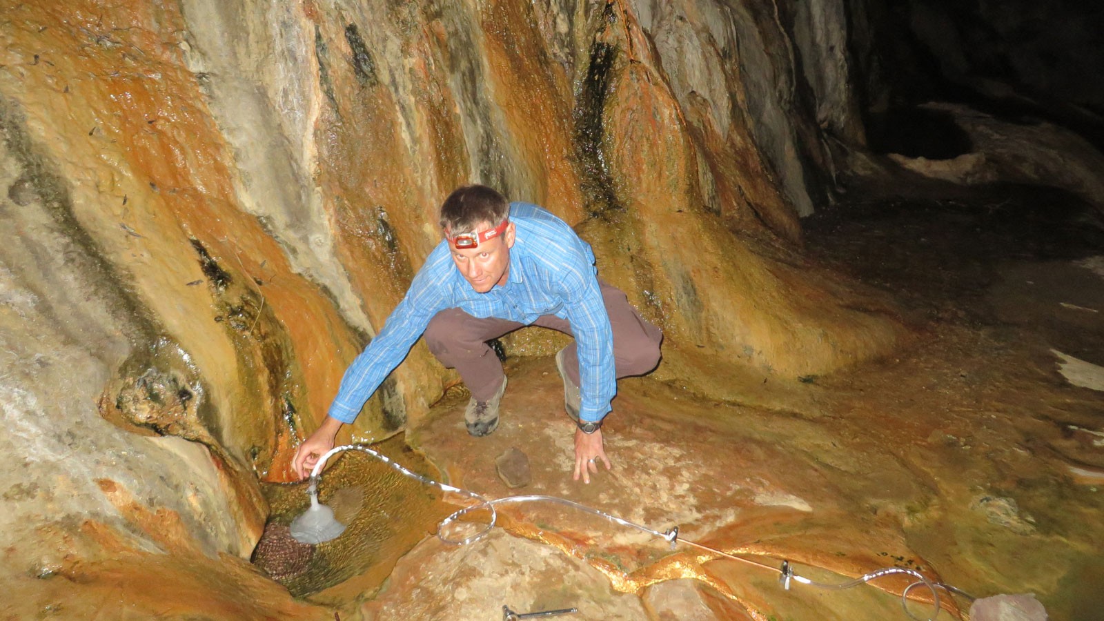Geoscientist collects gas sample from hot spring.