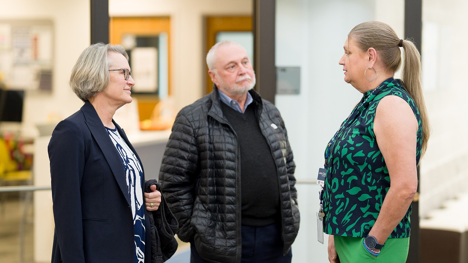 Three people stand and speak to each other